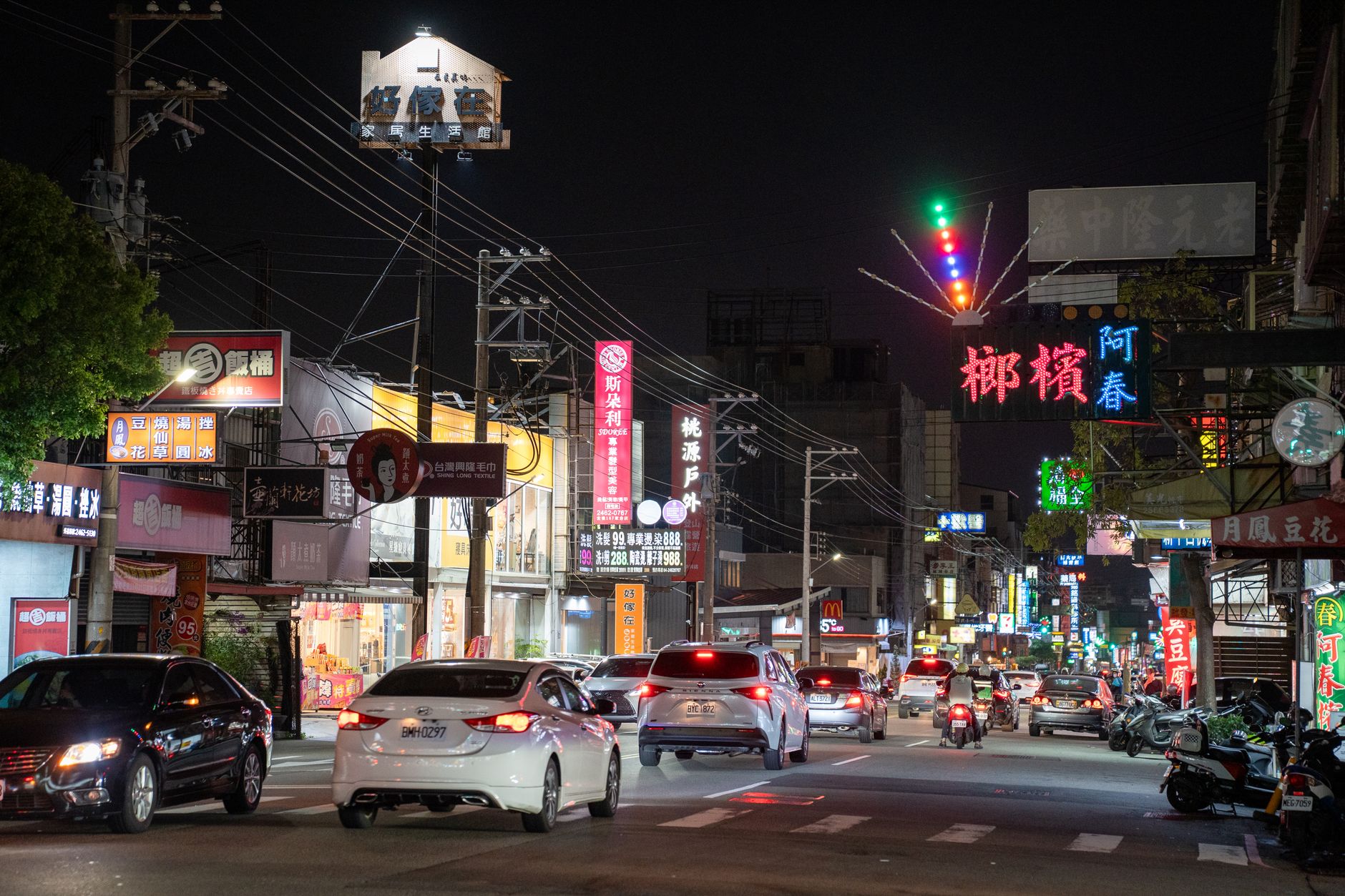 Bustling urban night scene with vibrant neon signs and traffic in a busy street.