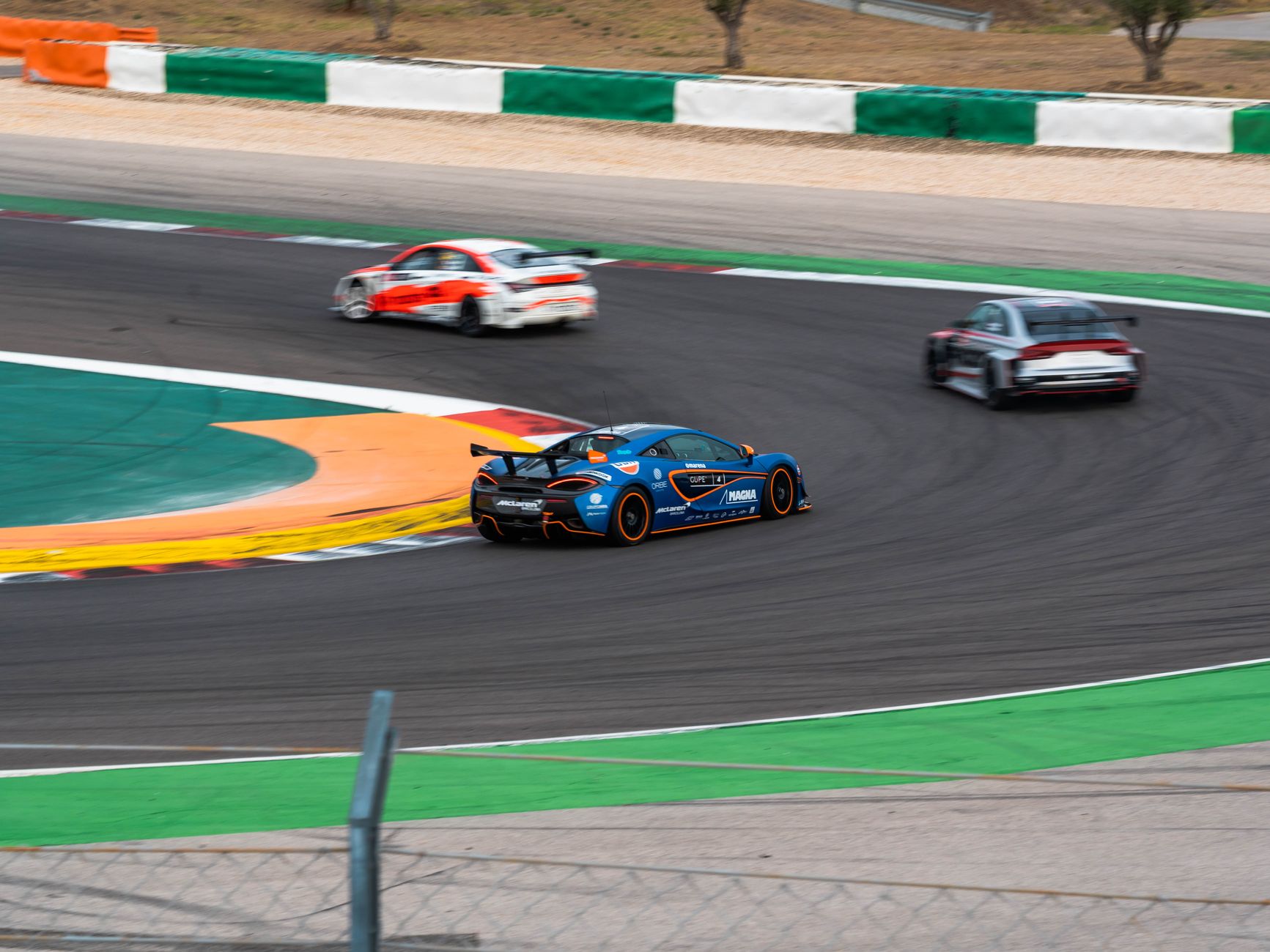 Exciting motorsport action with race cars speeding on a curved track.