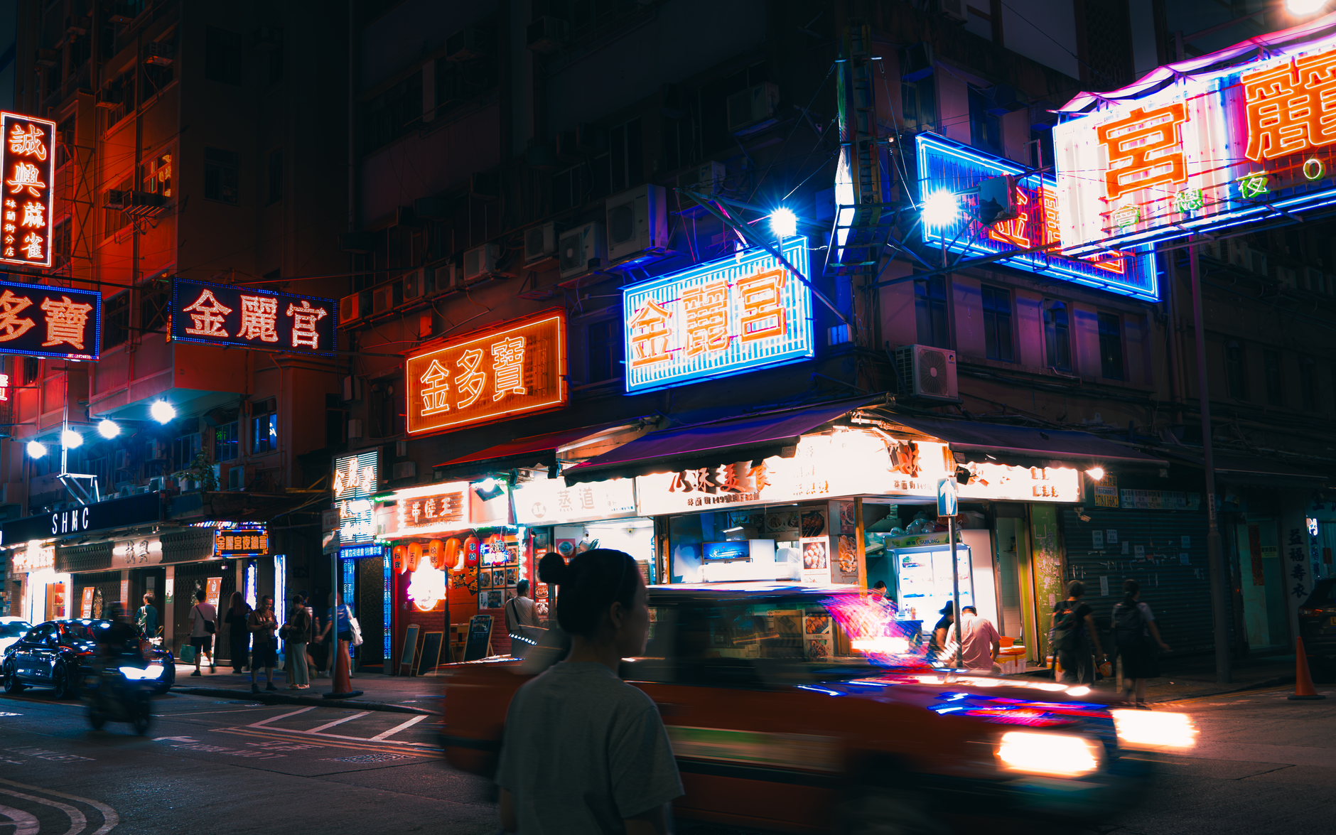 Multicolored neon lights illuminate bustling streets of Kowloon, Hong Kong at night.