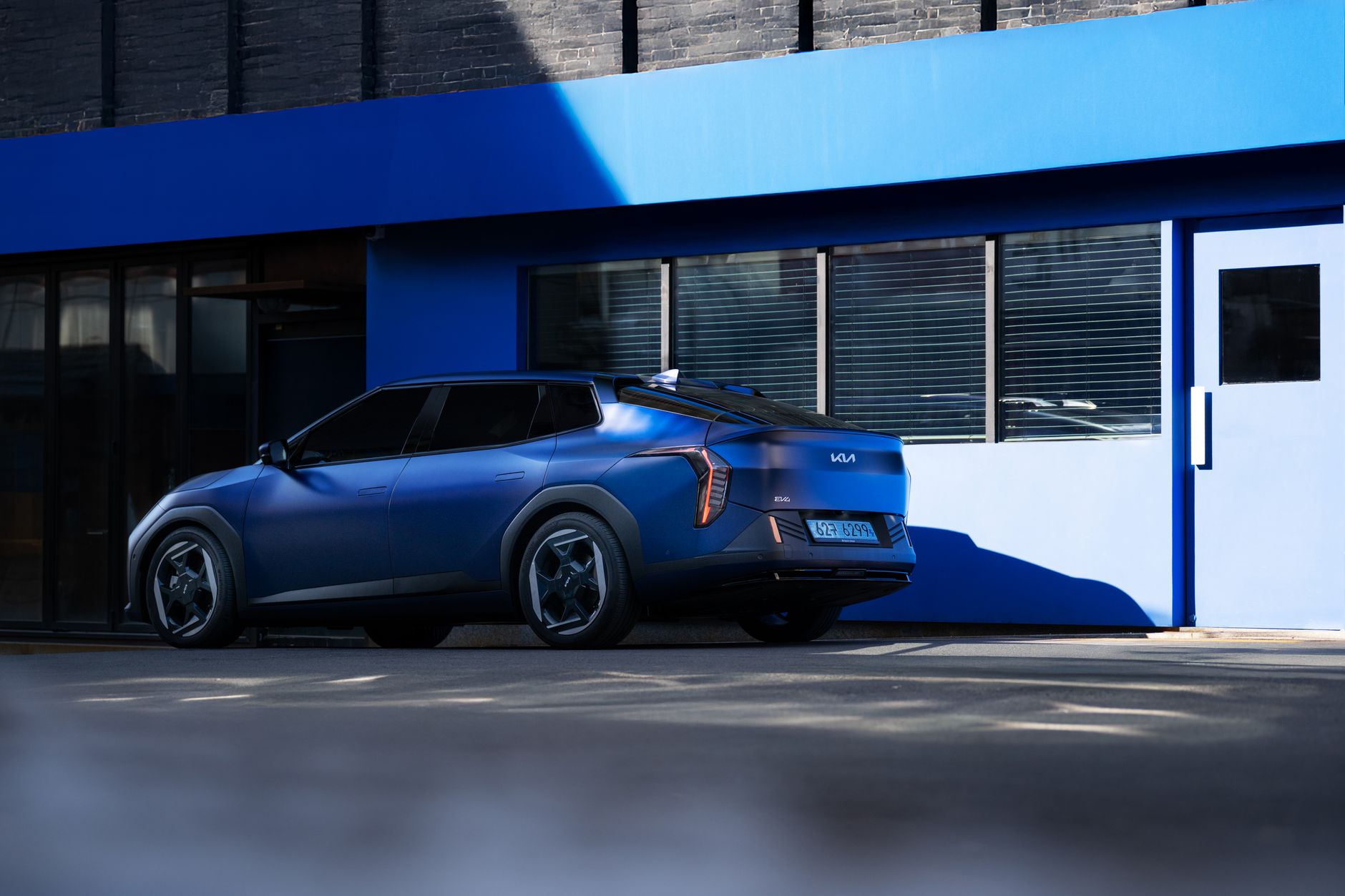 A modern blue electric vehicle parked outside a contemporary building on a sunny day.