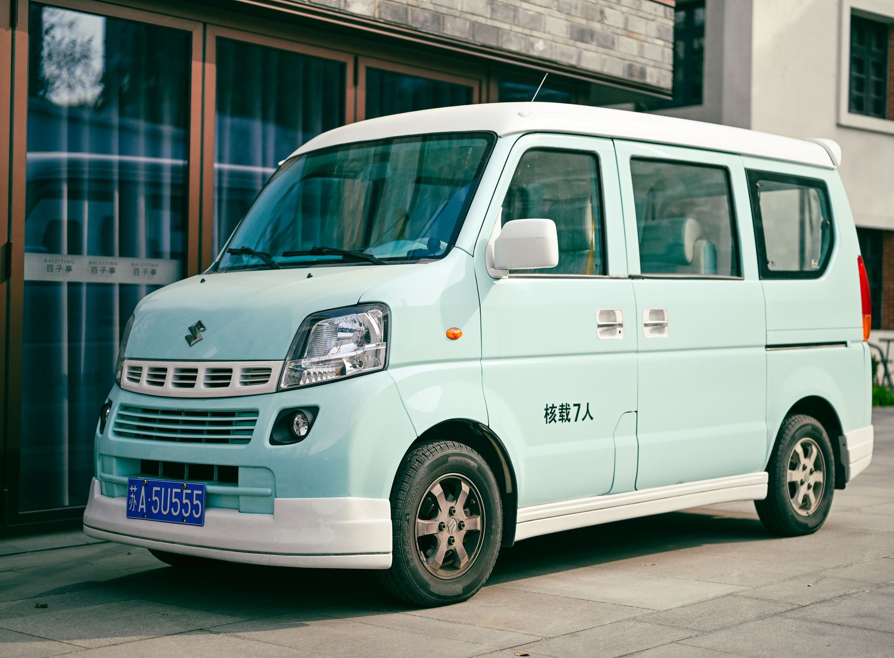 A light green Suzuki van parked outdoors in Nanjing, China with license plate visible.