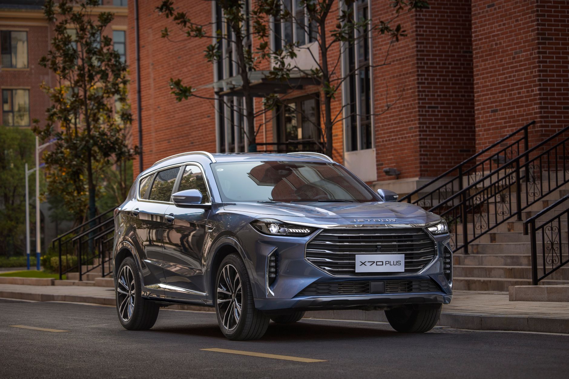 A sleek blue SUV parked on a city street, showcasing its modern design against a brick building.