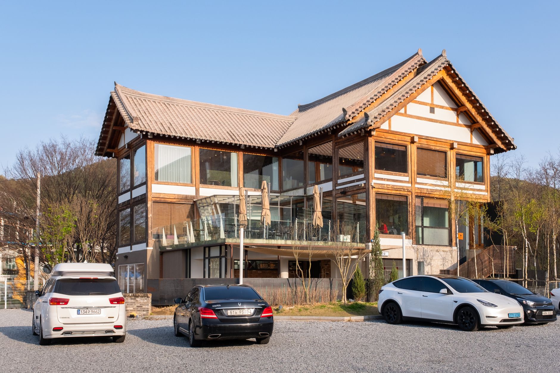 A traditional style building with parked modern cars under a clear blue sky.