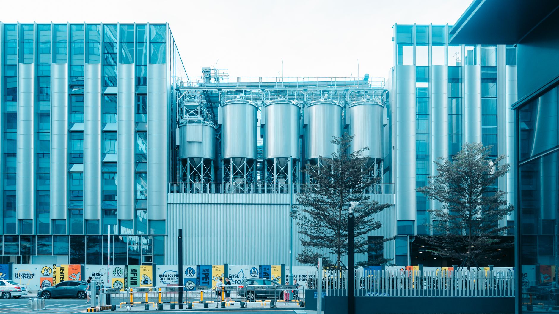 Contemporary industrial building with steel silos and urban surroundings in daylight.