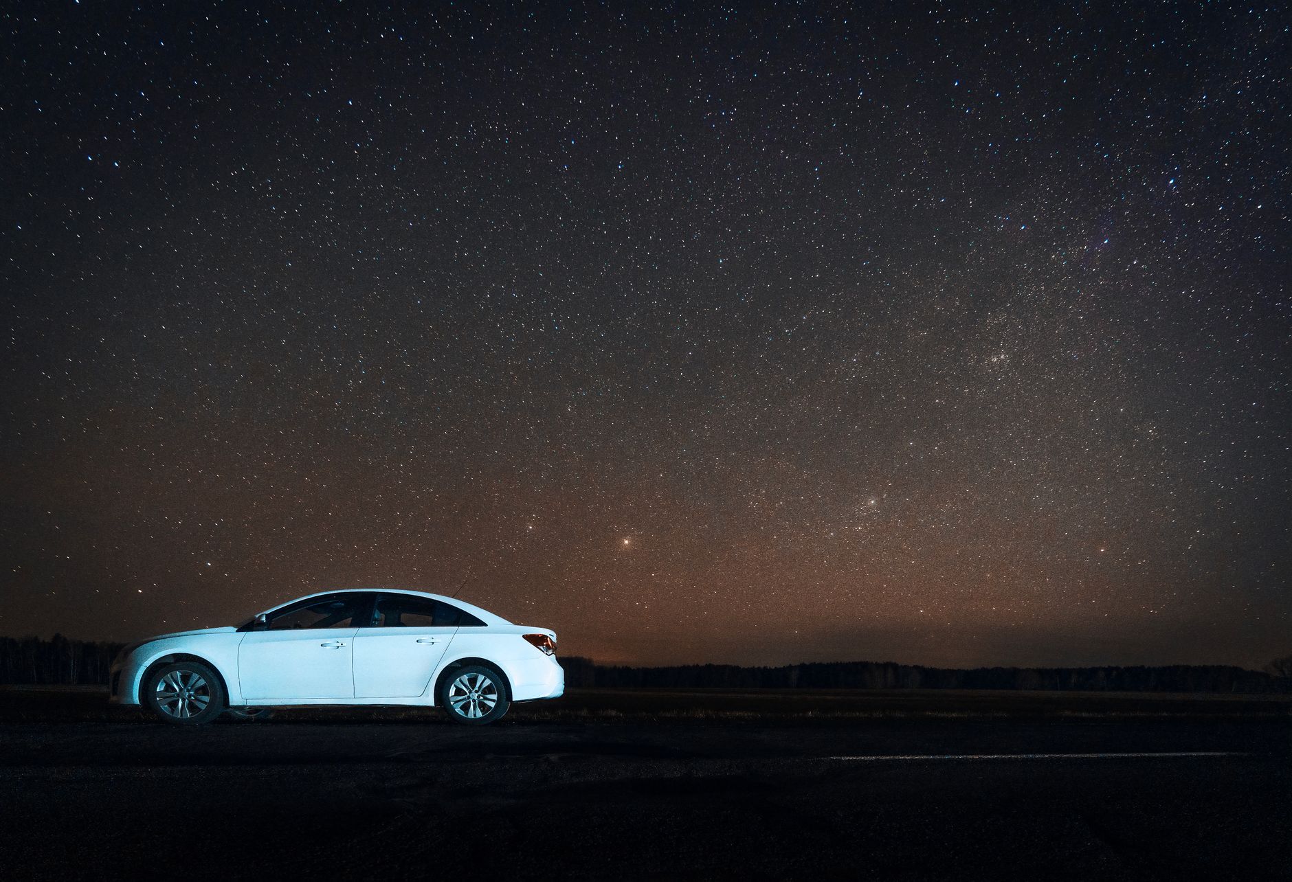 White car parked under a stunning starry sky in Sosenka, Belarus, creating a mesmerizing night view.