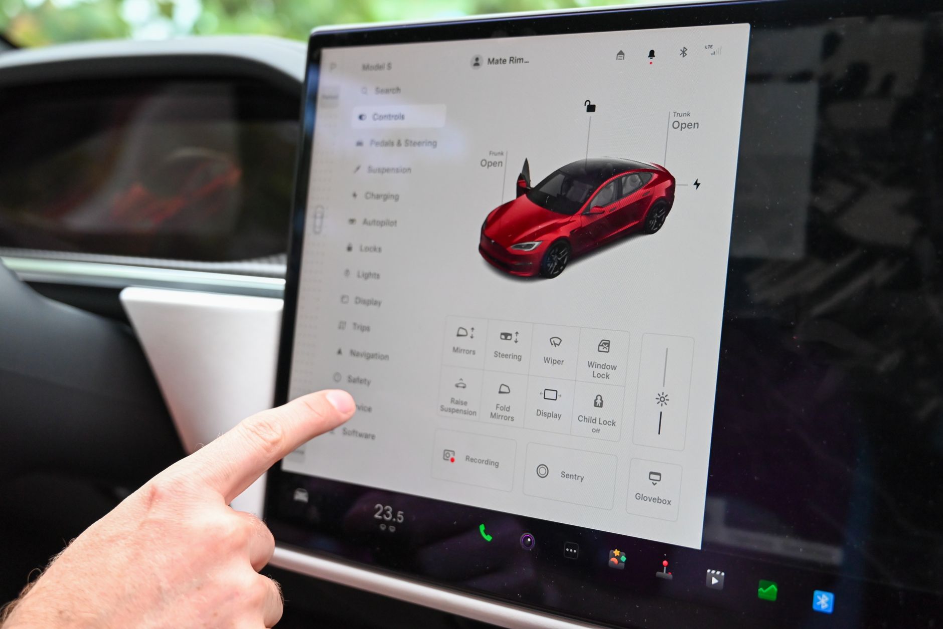 Close-up of a hand interacting with a modern car's touchscreen interface for various controls.