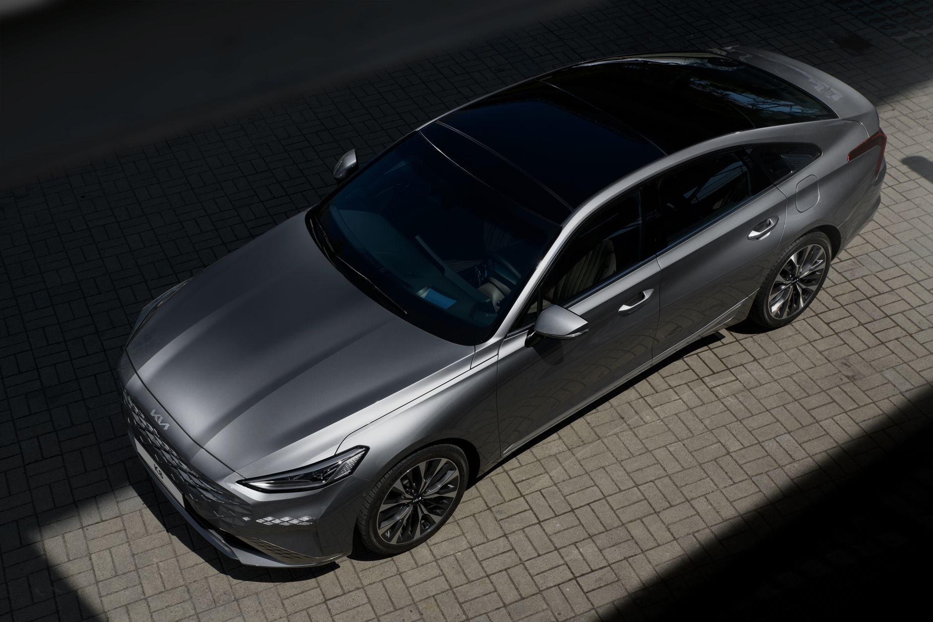 A modern silver sedan parked on a paved surface under sunlight, showcasing its sleek design.