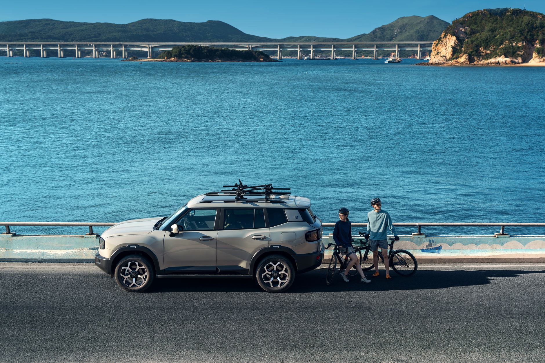 A sleek SUV parked by the sea with bicycles, overlooking a stunning coastal view.