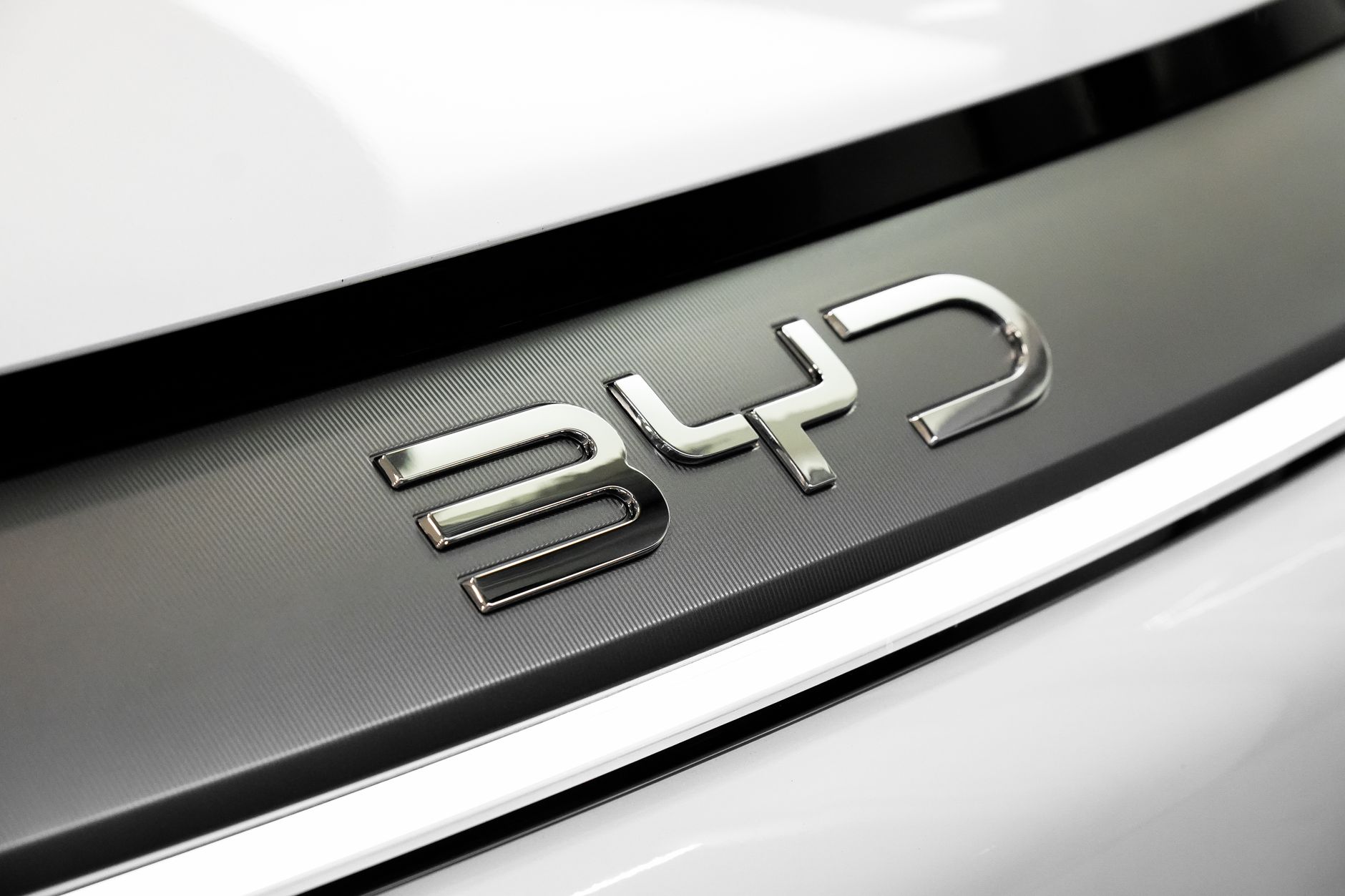 Detailed close-up of the chrome BYD logo on a car, showcasing sleek automotive branding.