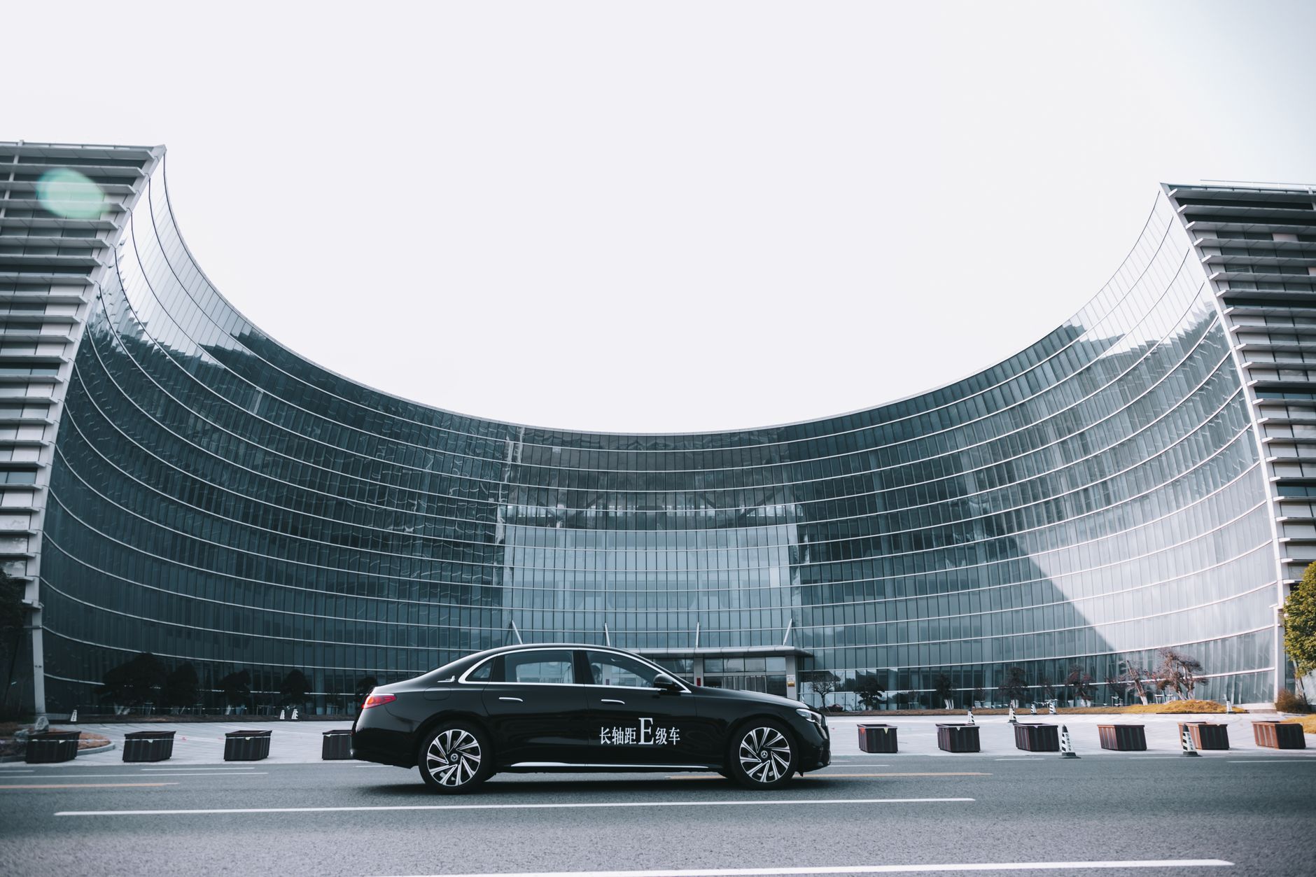 Sleek black luxury car parked outside a modern architectural glass structure, conveying elegance and urban sophistication.