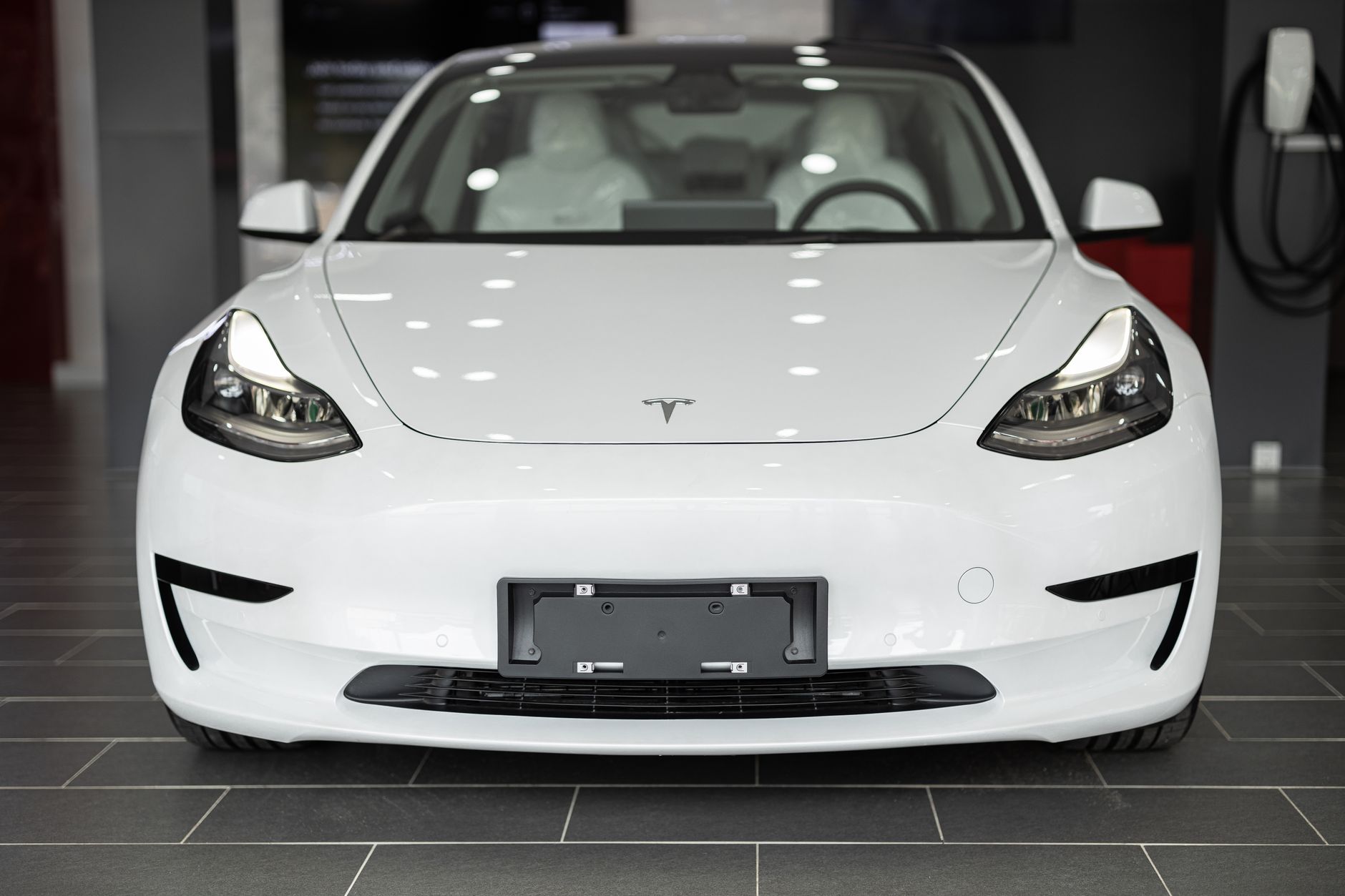 Sleek white electric car on display in a modern dealership showroom.