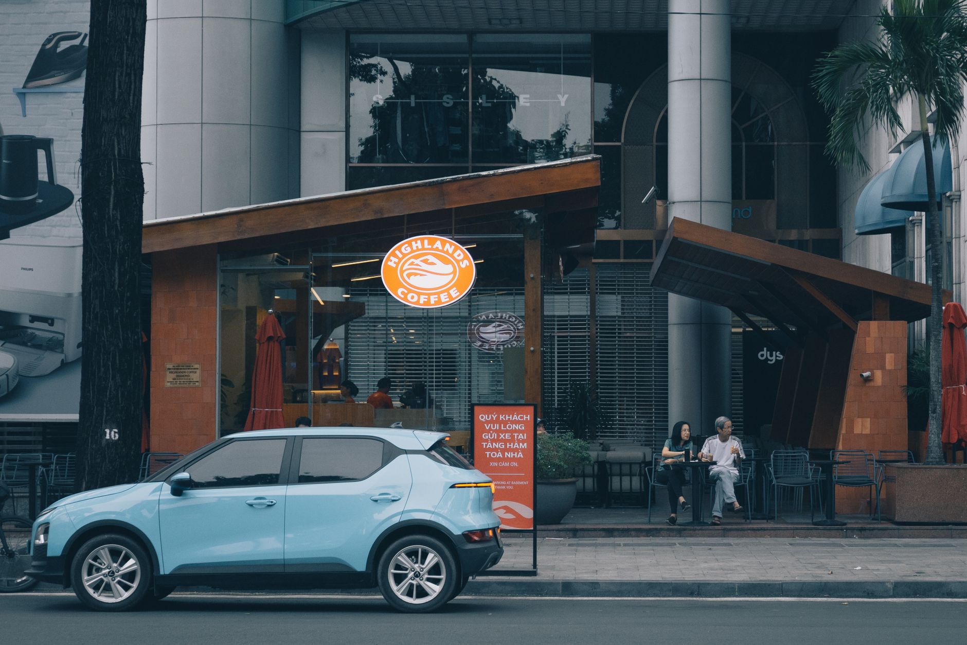Electric car parked outside a modern cafe in bustling Ho Chi Minh City, Vietnam.