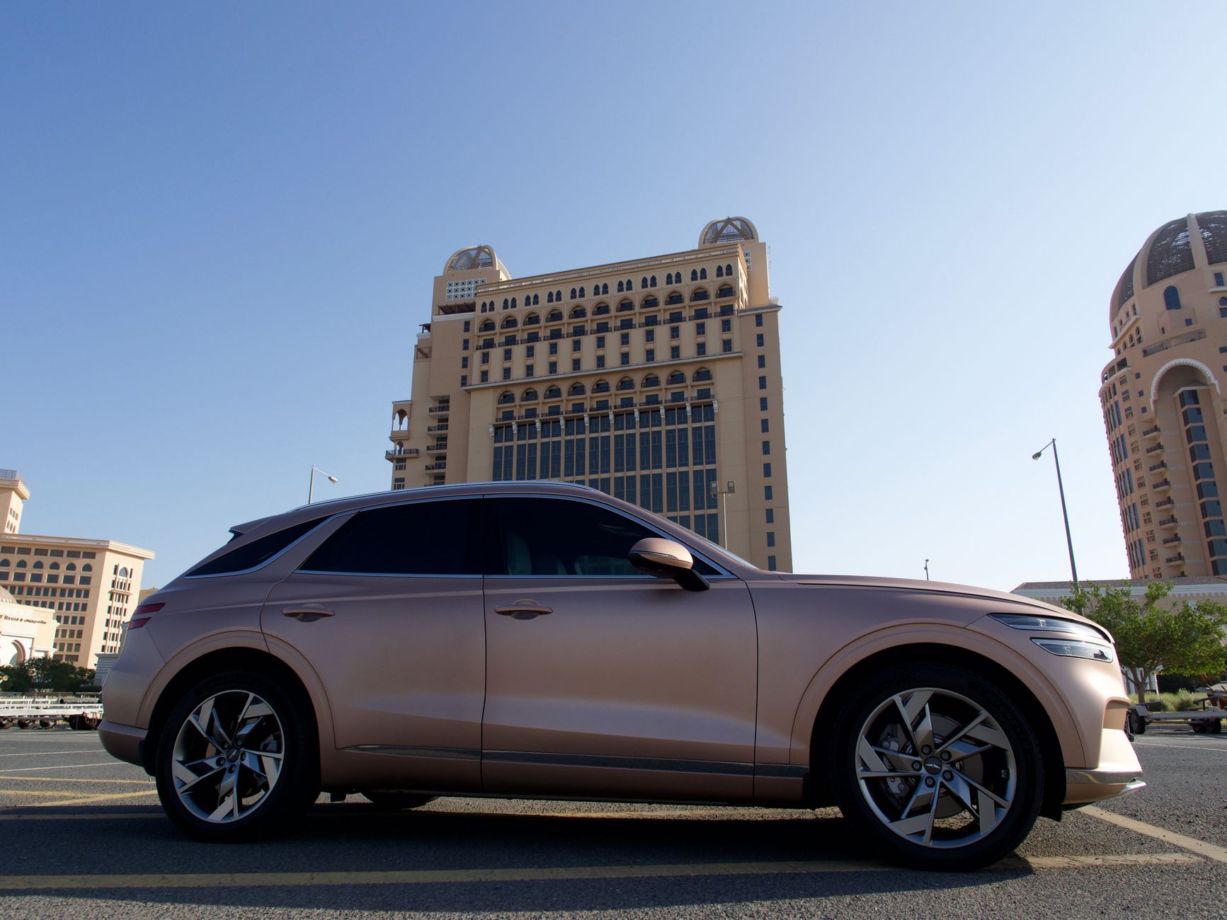 Elegant luxury SUV with modern design in front of Doha's distinctive architecture.