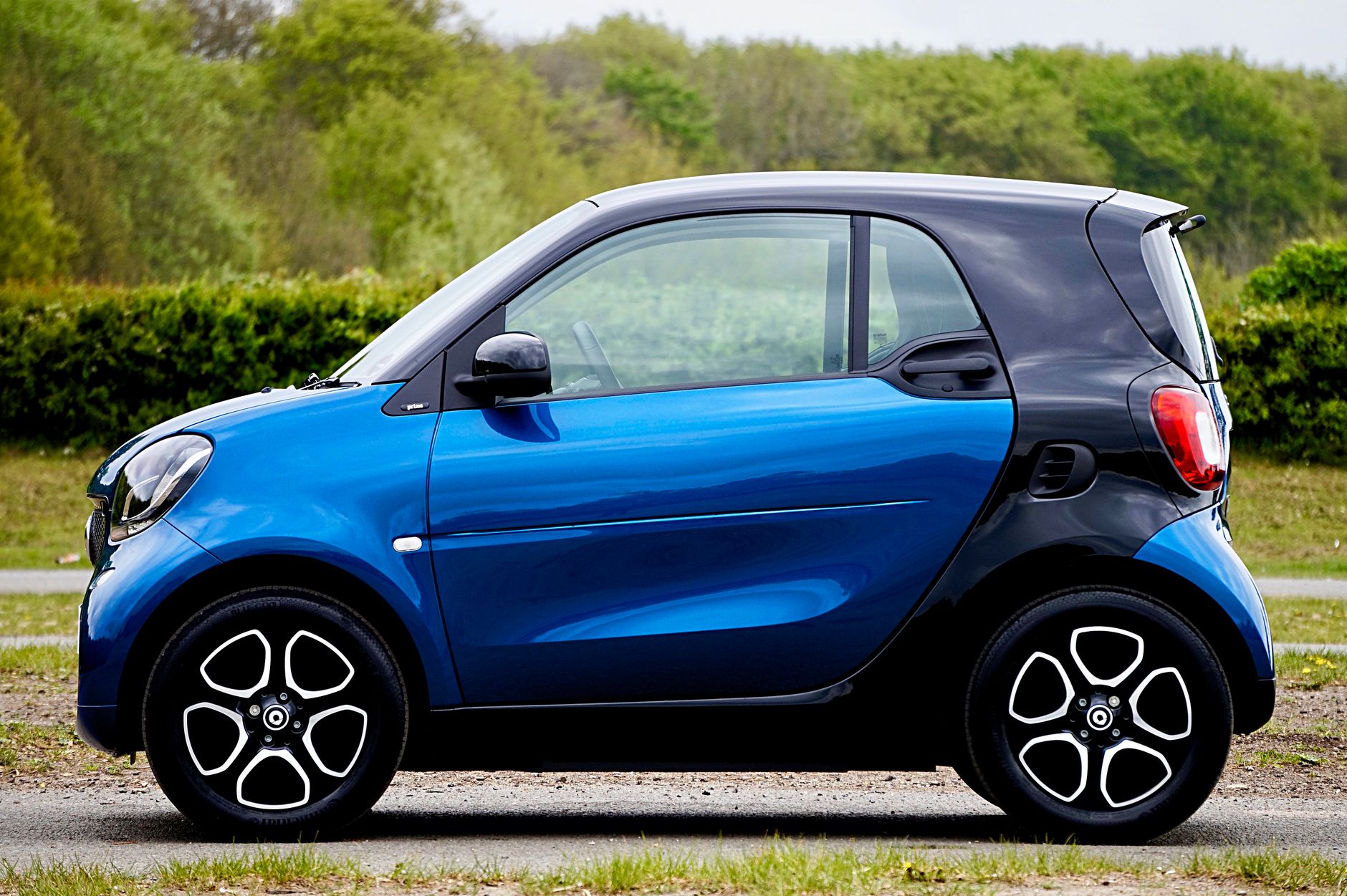 Side view of a blue smart car in the UK outdoors. Compact and stylish vehicle design.