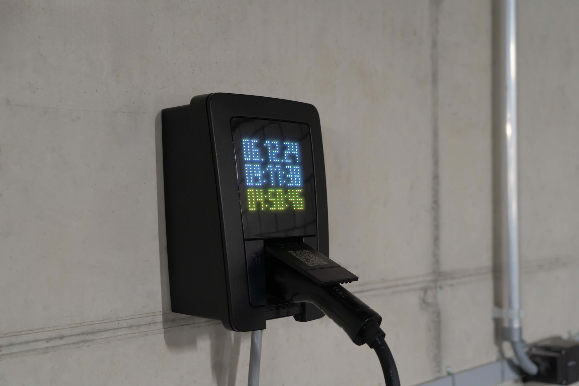 Close-up of an electric car charging station with digital display showing charge stats.