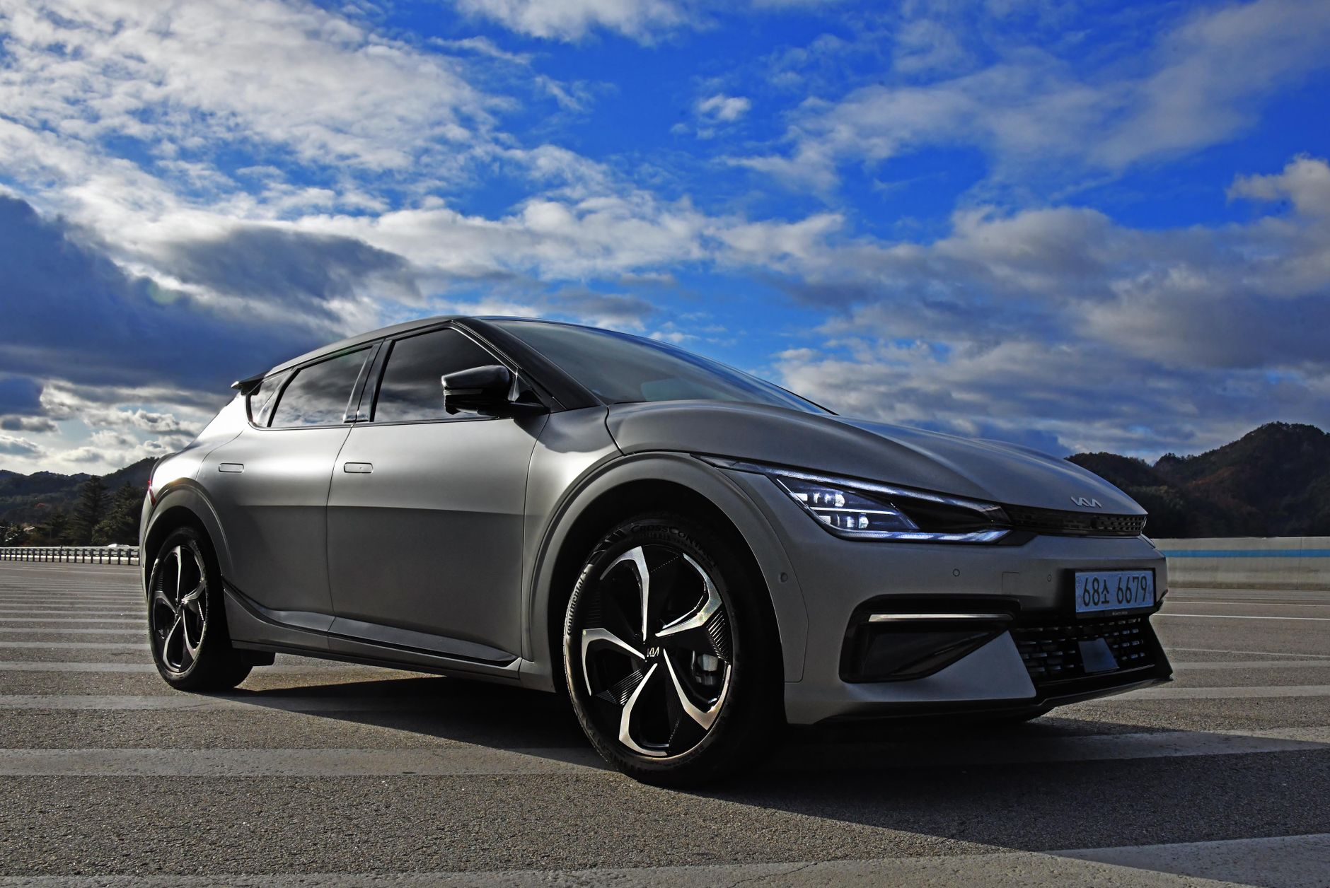 A sleek electric Kia EV6 parked outdoors against a stunning sky and landscape.