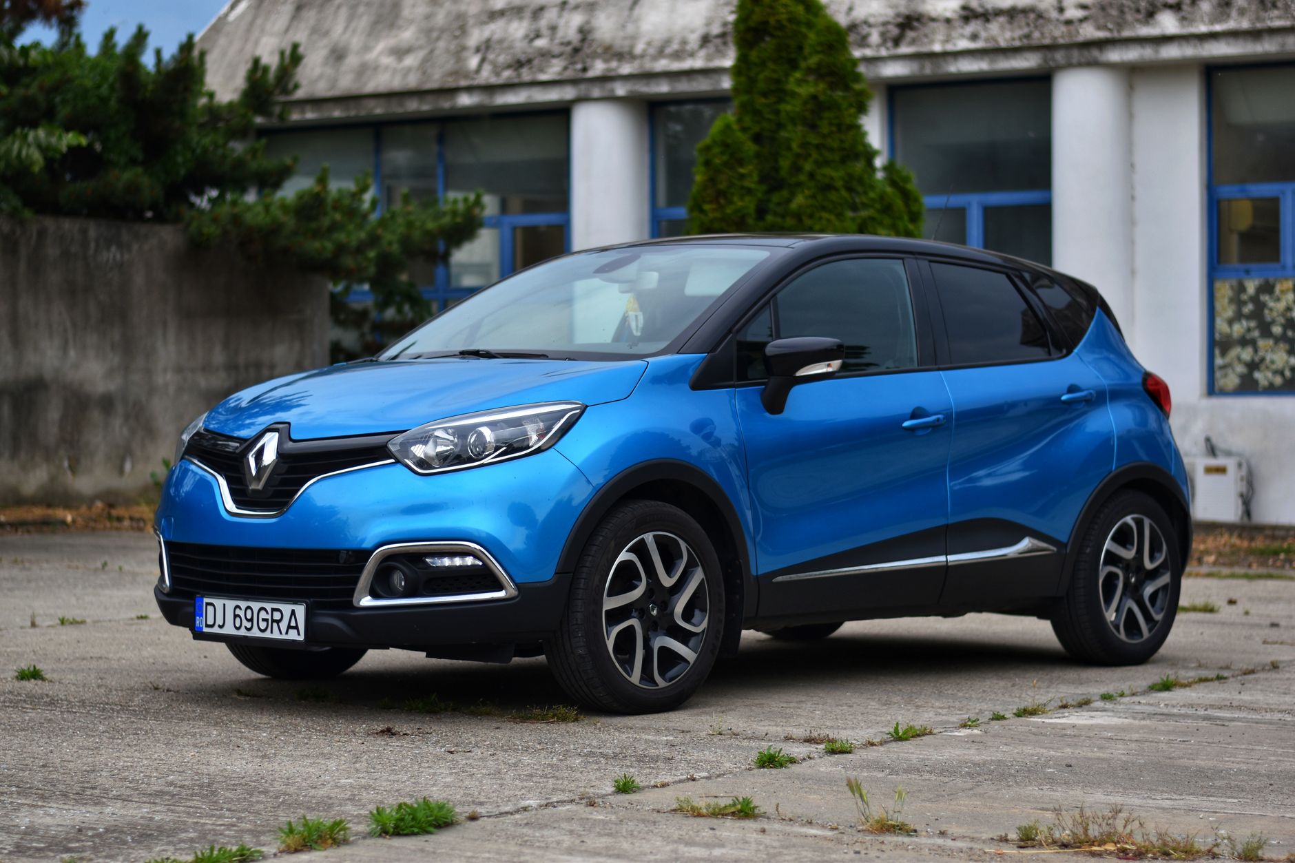 A sleek blue Renault Captur parked in front of a building, showcasing its modern design.