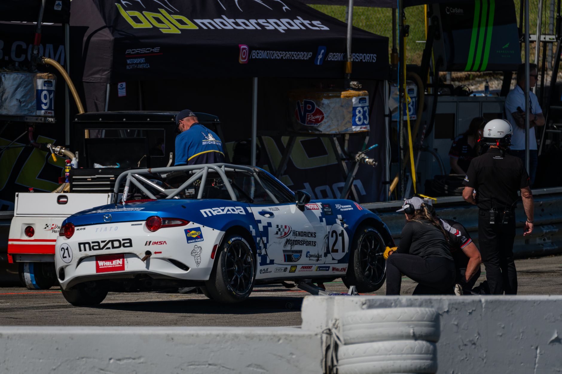 White and blue Mazda sports car in a pit stop at a racing event in Lexington, Ohio.