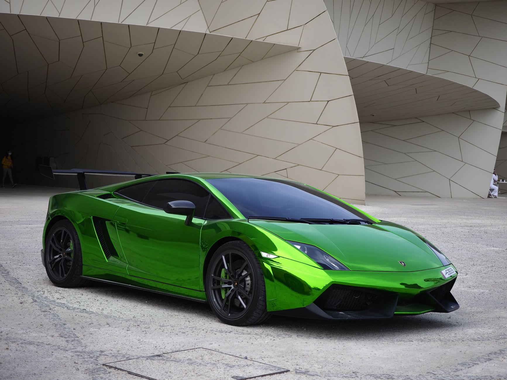 Shiny green sports car parked outside modern architecture in Doha, Qatar.